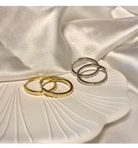 Vista macro di orecchini a cerchio minimalisti in oro e argento su un piatto a conchiglia