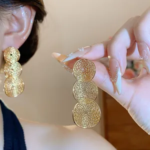 Detailansicht goldener runder Ohrhänger mit feinem Hohlmuster-Design