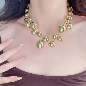 Detailed view of a stylish irregular gold chunky beaded necklace worn on a model's neck