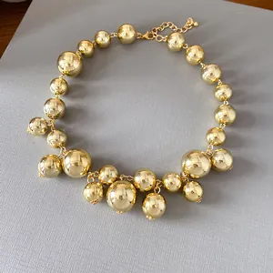 Chunky irregular golden bead necklace with high-gloss metallic finish on grey board