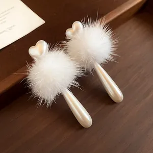 Detailed macro shot of white faux fur pom-pom earrings with elegant heart pearl drops
