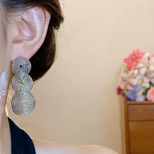 Detailaufnahme von eleganten silbernen, hohlen, runden Tropfenohrringen an einem Modelohr