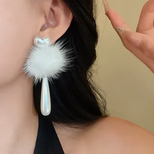 Detail view of white heart pearl and fur ball drop earrings with elegant winter aesthetic