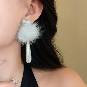 Detail view of elegant heart earrings with white fur pom-poms and teardrop faux pearls.