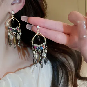 Detailed macro shot of vintage gold chandelier earrings with long tassel and colorful beads.
