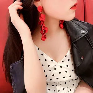 Orecchini pendenti a petalo di rosa rossa indossati da una modella in giacca di pelle.