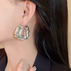 Close-up of U-shaped silver hoop earring with rectangular baguette crystals on ear