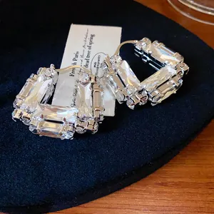 Close-up of elegant U-shaped hoop earrings featuring large rectangular clear crystals.