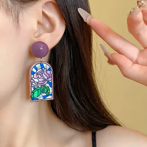 Gros plan de boucles d'oreilles roses style vitrail vintage avec puce violette