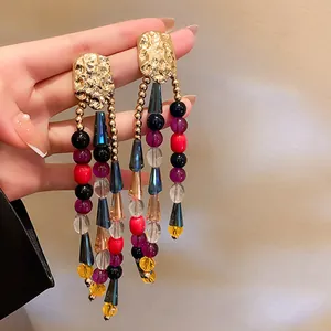 Detailed view of vintage long tassel earrings with colorful beads and hammered gold metal