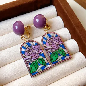 Vue détaillée de boucles d'oreilles vintage en vitrail avec rose dans un coffret