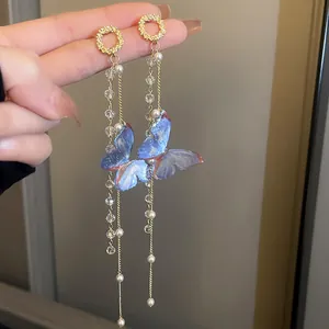 Detailed macro view of blue mesh butterfly earrings featuring long elegant beaded tassels