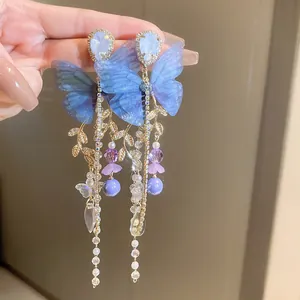 Close-up of elegant blue mesh butterfly earrings featuring long crystal tassels and beads