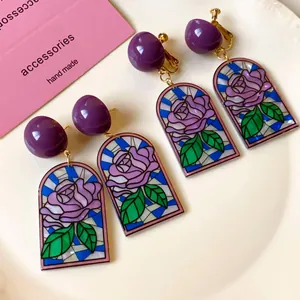 Détail macro de boucles d'oreilles rétro en vitrail rose, finitions or et violettes