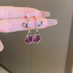 Close-up of elegant gold drop earrings with purple gradient crystal teardrops