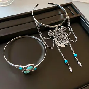 Detailed view of bohemian silver arm ring with tassels and turquoise bangle on a black tray