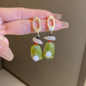 Close-up of vintage green marble-effect drop earrings featuring a delicate white rose.