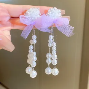 Close-up view of elegant purple mesh bow earrings featuring long dangling white pearl tassels