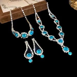 Elegant jewelry set with blue rhinestones featuring necklace, bracelet, and earrings