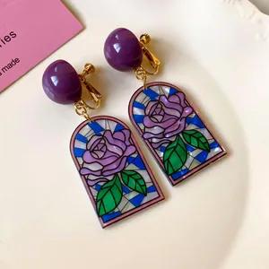 Détail de boucles d'oreilles vintage avec motif de rose en vitrail et accents violets