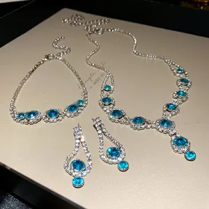 Elegant jewelry set with blue rhinestones including necklace, bracelet, and earrings.