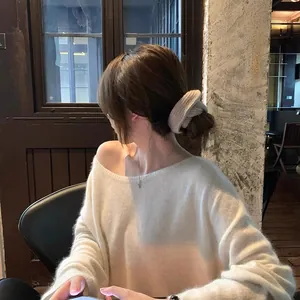 Detailed side view of a stylish beige knitted scrunchie styled on a messy hair bun