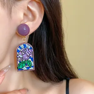 Gros plan détaillé de boucles d'oreilles vintage en vitrail rose avec perle violette
