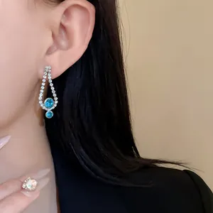 Close-up of elegant drop earrings with blue rhinestones worn by a model