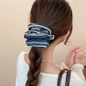Retro navy patterned fabric scrunchie shown on a braided ponytail detail view hair.