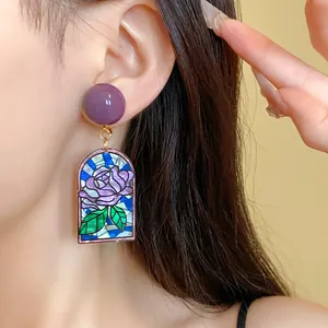 Gros plan de boucles d'oreilles vintage style vitrail avec un motif de rose violette.