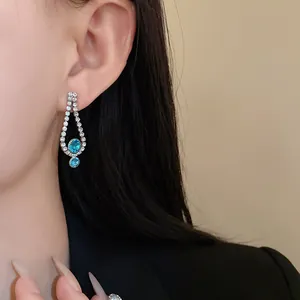 Close-up of elegant silver-tone teardrop earrings featuring vibrant blue crystals