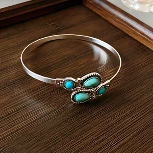 Close-up detail of a vintage silver-toned open bangle set with teardrop turquoise stones
