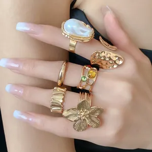 Elegante conjunto de anillos abiertos de metal dorado con flores y detalles de perlas