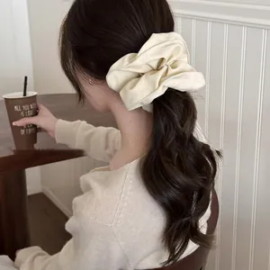 Elegant cream oversized leather-style scrunchie on a low ponytail hair styling detail
