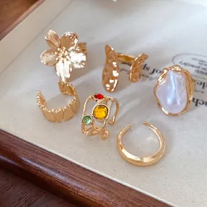 Elegante conjunto de anillos dorados con flores texturizadas y perlas para mujer