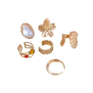 Set de 6 anillos abiertos metálicos dorados con diseños de flores y perlas texturizadas
