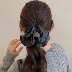 Detail of large dark grey scrunchie on brown hair with grey knit sweater