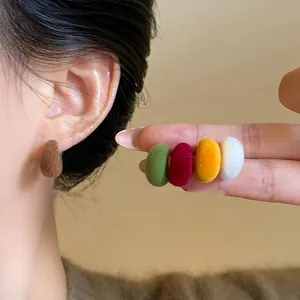 Close-up of colorful flocked C-shaped earrings showing soft velvet texture and colors.