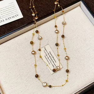 Close-up of retro beaded sweater chain with irregular champagne and brown beads.