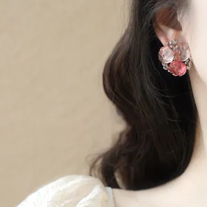 Gros plan d'élégantes boucles d'oreilles fleurs roses portées par un mannequin
