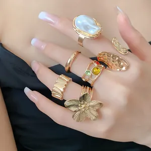 Primer plano de anillos dorados con diseño de flor plisada y piedras de colores
