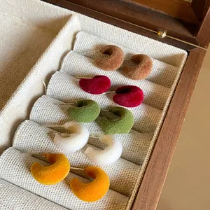 Detail of colorful flocked C-shaped hoop earrings organized in a vintage wooden jewelry box