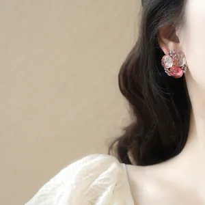 Gros plan sur d'élégantes boucles d'oreilles à fleurs roses portées par un mannequin.