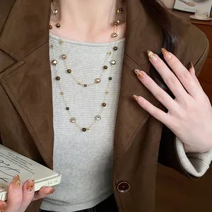 Detailed view of an irregular geometric beaded necklace on a vintage-style brown blazer