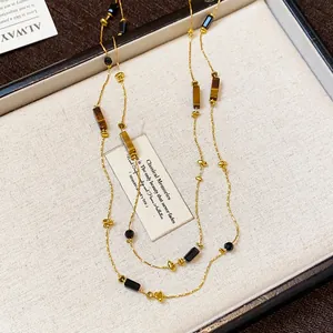 Detail of retro long necklace with geometric black and tiger eye beads