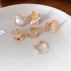 Detalle de varios anillos abiertos dorados con texturas florales y plisadas
