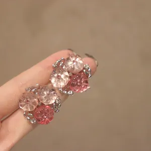 Gros plan de puces d'oreilles fleurs roses avec tige en argent et cristaux étincelants