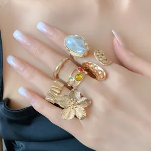 Vista detallada de anillos de flor dorados y alianzas texturizadas abiertas con perla