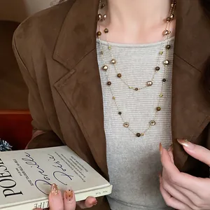 Detailed view of a vintage double-layered beaded sweater necklace worn on a brown blazer.