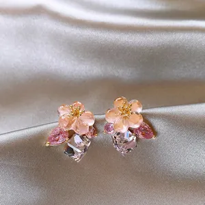 Detailed macro view of elegant pink flower stud earrings with hanging crystal gems.